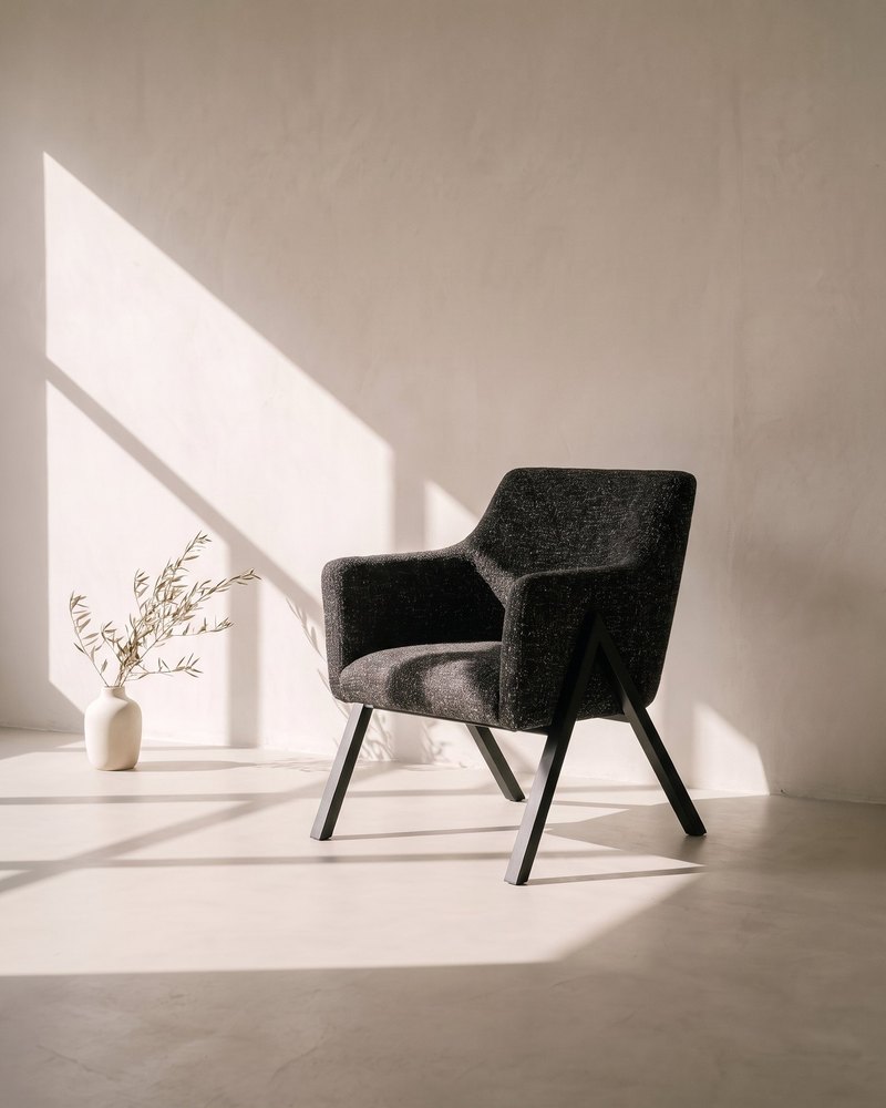 Silla AP junto a un jarrón de ramas secas en una galería de yeso hueso con luz de tarde y sombras de ventana